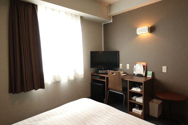 A hotel room with a bed, a desk with a computer, a television, and a small table. - Silk Hotel Annex (Iida)