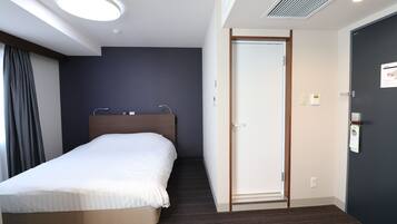 Et hotelværelse med en seng, en dør og en loftslampe.