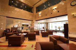 A spacious lobby with multiple seating areas, a reception desk, and a large clock on the wall. - Silk Hotel Annex (Iida)