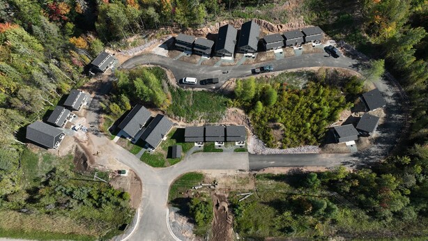 Vista aérea de una zona residencial con varias casas, calles y un estacionamiento.
