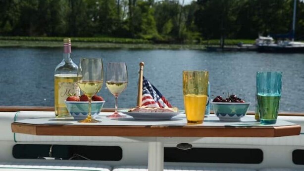 A table with a bottle, glasses, a plate with strawberries, and a flag on a boat. - Beautiful Yacht on Catskill Creek (Catskill)