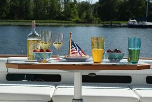Een tafel met een fles, glazen, een bord met aardbeien en een vlag op een boot.