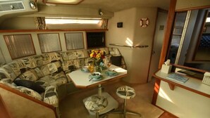 A compact RV interior with a kitchenette, a dining area, and a small seating space. - Beautiful Yacht on Catskill Creek (Catskill)