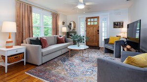 A living room with a sofa, armchairs, a coffee table, and a television.