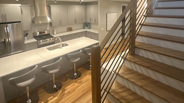 Una cocina moderna con una isla central, taburetes de bar y un refrigerador de acero inoxidable.
