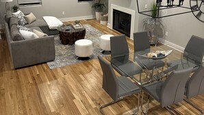 Una sala de estar moderna con un sofá gris, una mesa de comedor de vidrio y una chimenea.