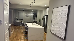 Una cocina moderna con una isla central, suelo de madera e iluminación empotrada.