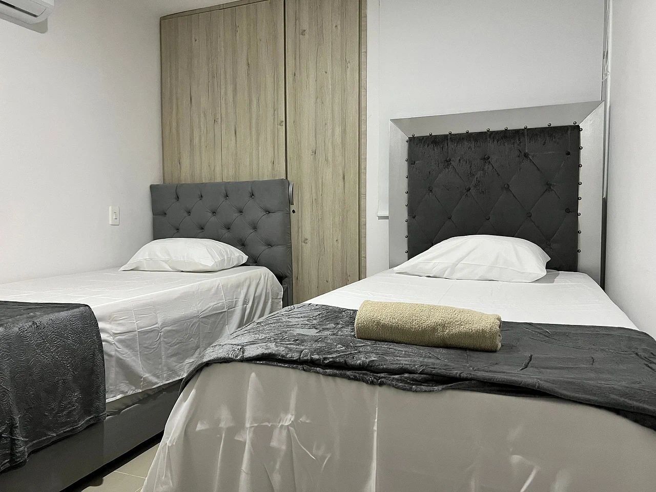 Two single beds with headboards, a wooden panel wall, and a white ceiling.