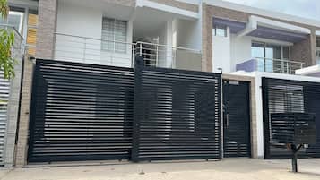 Un immeuble résidentiel moderne doté d’une entrée sécurisée, d’un balcon et de fenêtres bien visibles.
