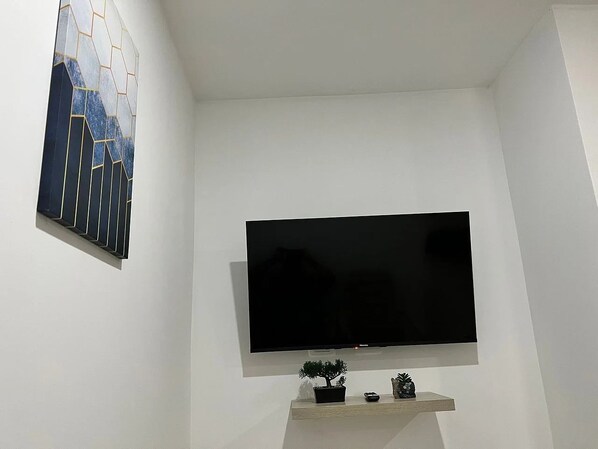 Un televisor de pantalla plana montado en la pared con un pequeño estante debajo.