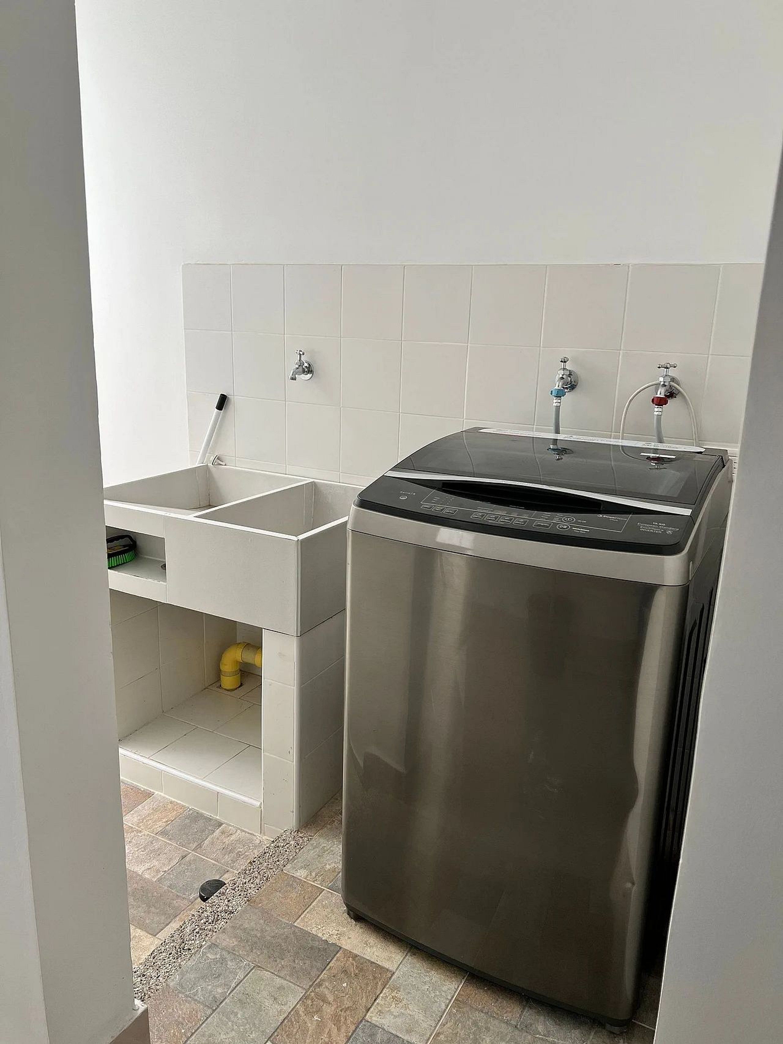 A compact kitchen with a stainless steel sink, a built-in dishwasher, and a tiled backsplash.
