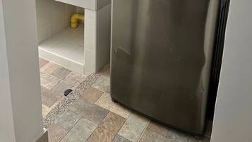 A compact kitchen with a stainless steel sink, a built-in dishwasher, and a tiled backsplash.