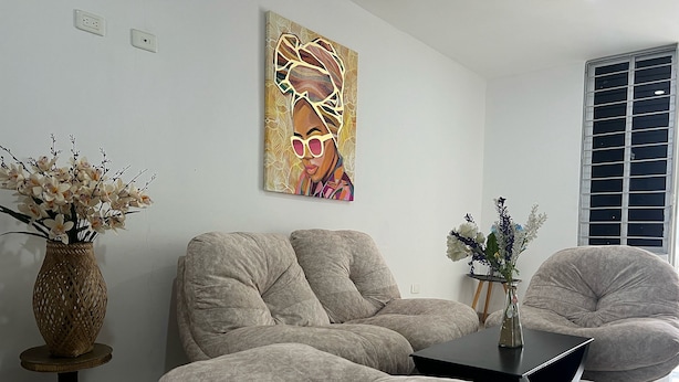 A modern living room with a sofa, armchairs, a coffee table, and a painting on the wall.