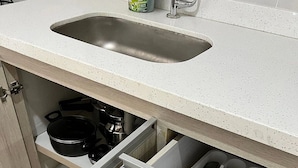 A kitchen with a sink, a stove, and drawers containing utensils.
