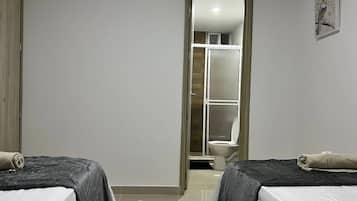 Una habitación con dos camas, ducha y baño.