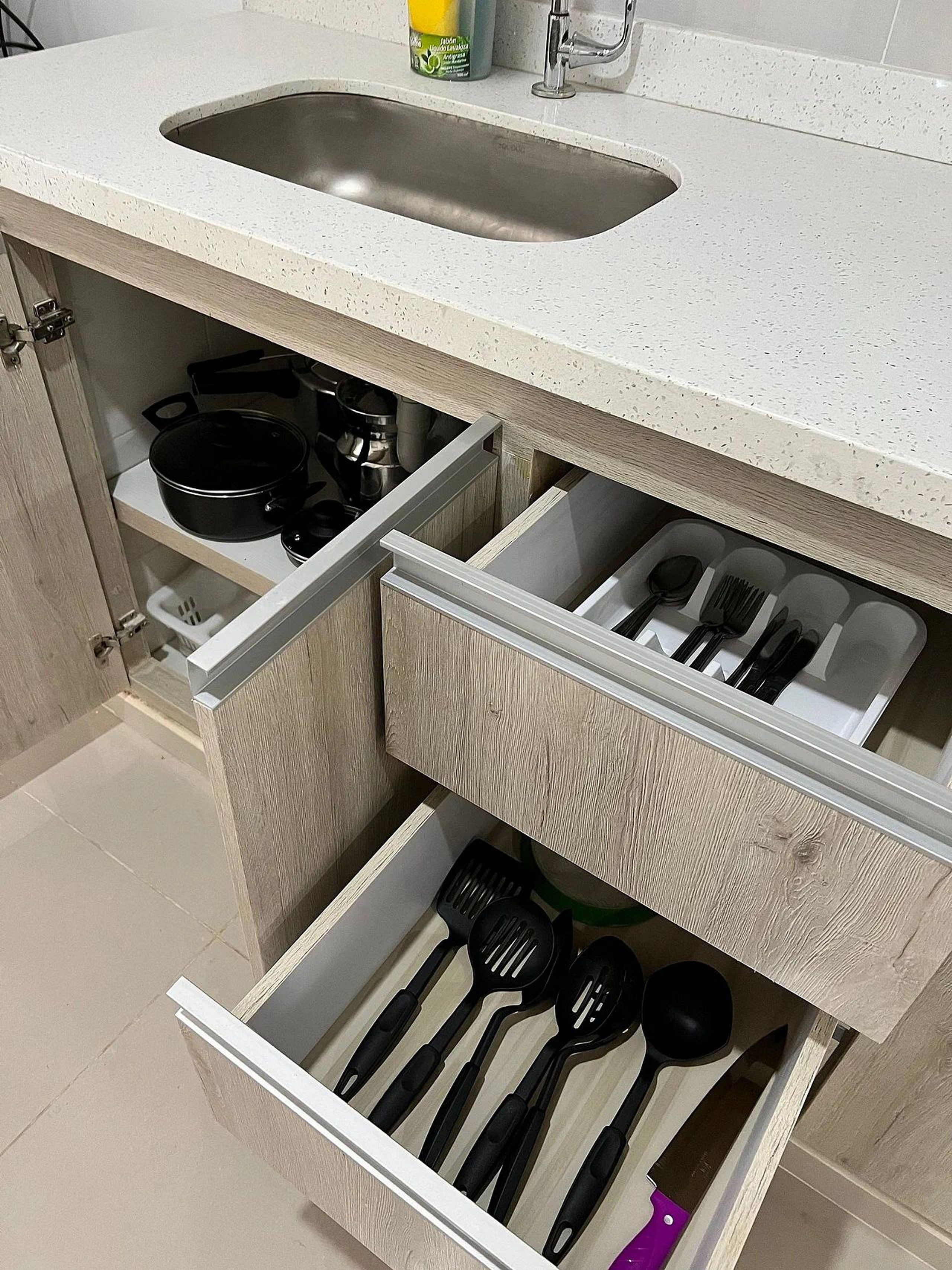 Una cocina con un lavamanos, una estufa y cajones con utensilios.