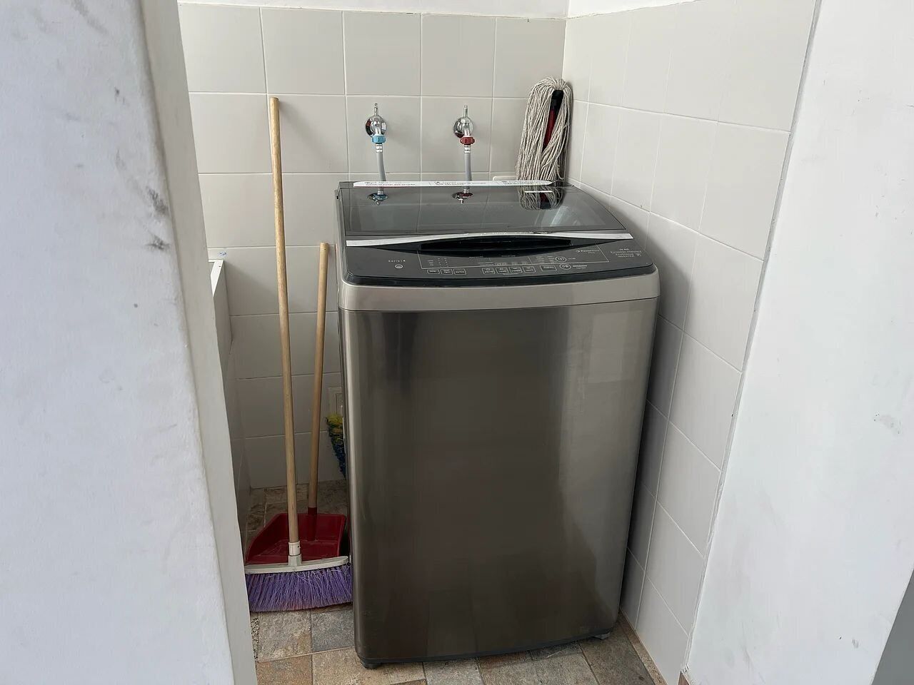 A compact, stainless steel appliance in a corner, likely a dishwasher, with two faucets on top.