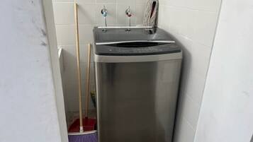 A compact, stainless steel appliance in a corner, likely a dishwasher, with two faucets on top.
