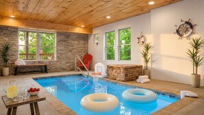 A pool area with stone walls, a wooden ceiling, and a bench with towels. - Heavenly Heights by Ghosal Luxury Lodging (Sevierville)