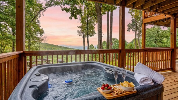 A hot tub with a wooden deck, surrounded by trees and a scenic view. - Heavenly Heights by Ghosal Luxury Lodging (Sevierville)