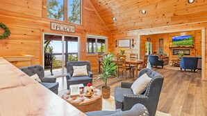 A wooden cabin interior with a dining area, seating, and a fireplace.
