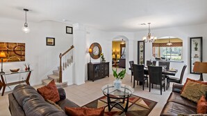 Ein geräumiges Wohnzimmer mit einer Ledersofa, einem Glastisch und einem Essbereich mit Stühlen und einem Tisch.