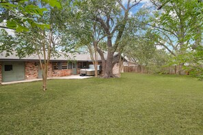 A house with a brick exterior, a covered patio, and a well-maintained lawn.