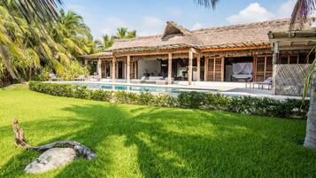 Un resort tropical con piscina, construcciones de techo de paja y exuberante vegetación.