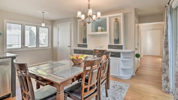 A modern kitchen with a dining area, featuring a central island, pendant lighting, and a view of the backyard. - Your TwinCities Memorable Stay (Saint Paul)
