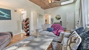 A spacious living room with a ceiling fan, a fireplace, and a view of the kitchen. - Your TwinCities Memorable Stay (Saint Paul)