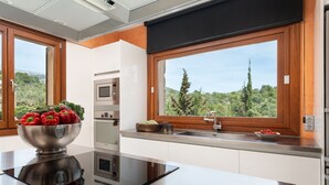 Cozinha moderna com uma bancada grande, eletrodomésticos de aço inoxidável e vista para o exterior.