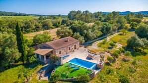 Eine Villa mit Swimmingpool, Steinarchitektur und umgebender Bepflanzung.