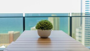 Una planta en maceta sobre una mesa de madera, con vista a la ciudad al fondo.