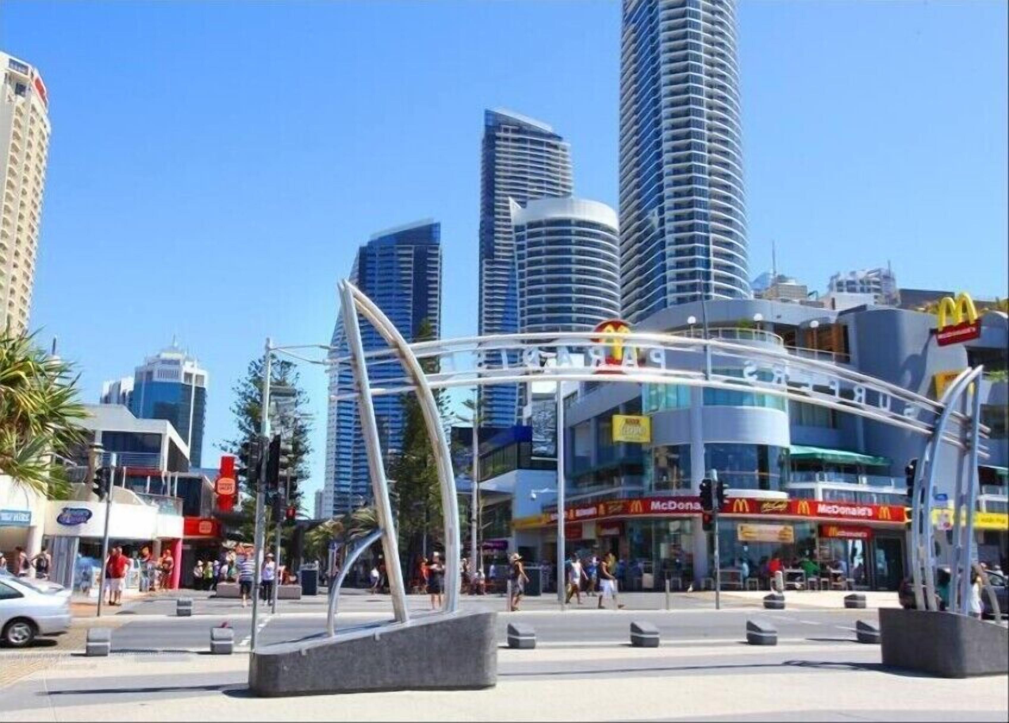 A modern urban plaza with a prominent curved structure, a McDonald's restaurant, and high-rise buildings in the background.