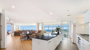 A modern kitchen with a central island, large windows, and a view of the sea. - Sub Penthouse 6203 - 3 bedrooms Level 62 (Gold Coast)