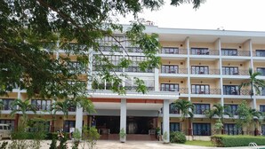 A multi-story hotel with balconies, a covered entrance, and a swimming pool. - Lisha Grand Riverside Hotel (Vang Vieng)