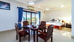 A hotel room with a dining area, a bed, and a view of the outdoors. - Lisha Grand Riverside Hotel (Vang Vieng)