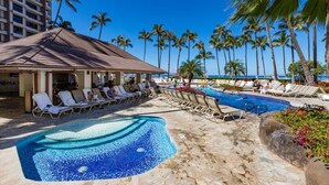 A hotel pool area with lounge chairs, a small pool, and palm trees.