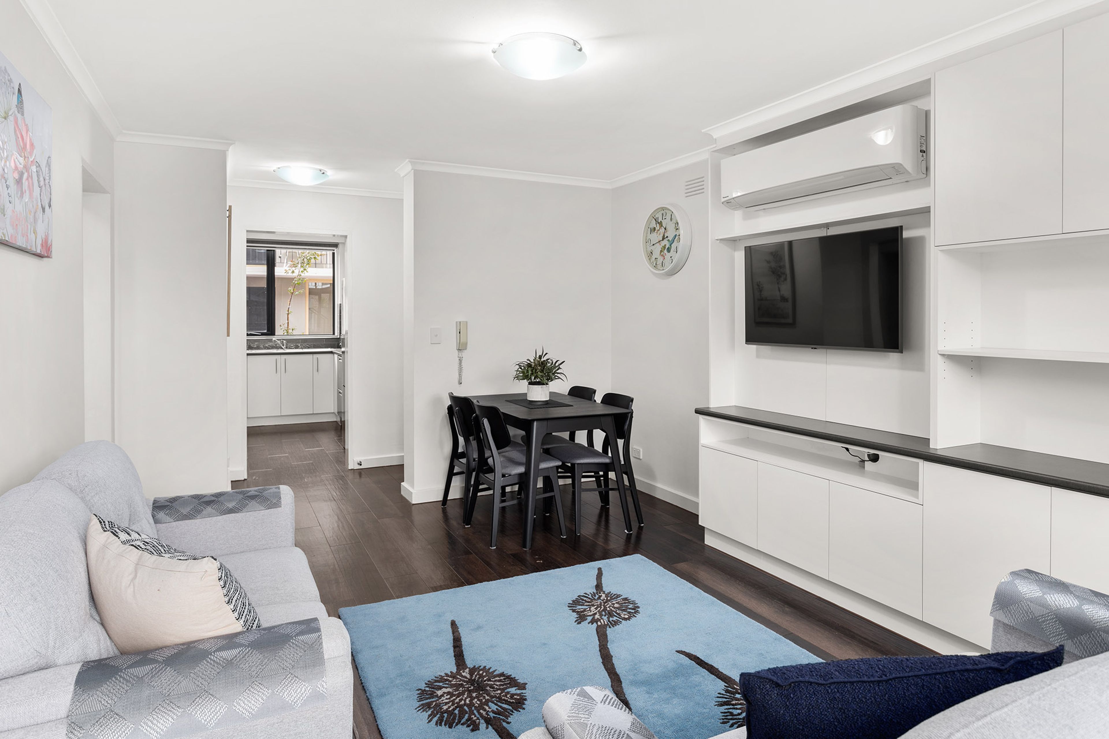 A modern living room with a sofa, a coffee table, and a dining area with chairs and a table.