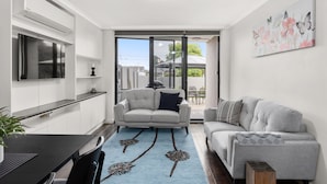 A modern kitchen with a built-in oven, a dining table with chairs, and a grey sofa with a patterned throw. - Lilly Pilly Pet Friendly Retreat in Essendon (Essendon)
