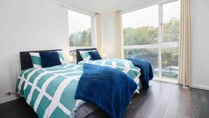 Une chambre avec deux lits, de grandes fenêtres et une vue sur l’extérieur.