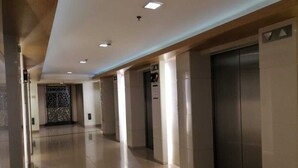 A modern hallway with elevators and a decorative wall. - Cozy Urban Apartment in Pasay City (Pasay City)