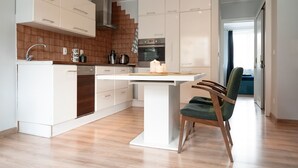 Una cocina moderna con armarios blancos, una isla central y una silla de madera.