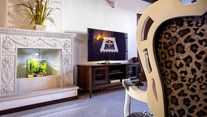 Ett vardagsrum med en öppen spis, en tv och en fåtölj med leopardmönster.
