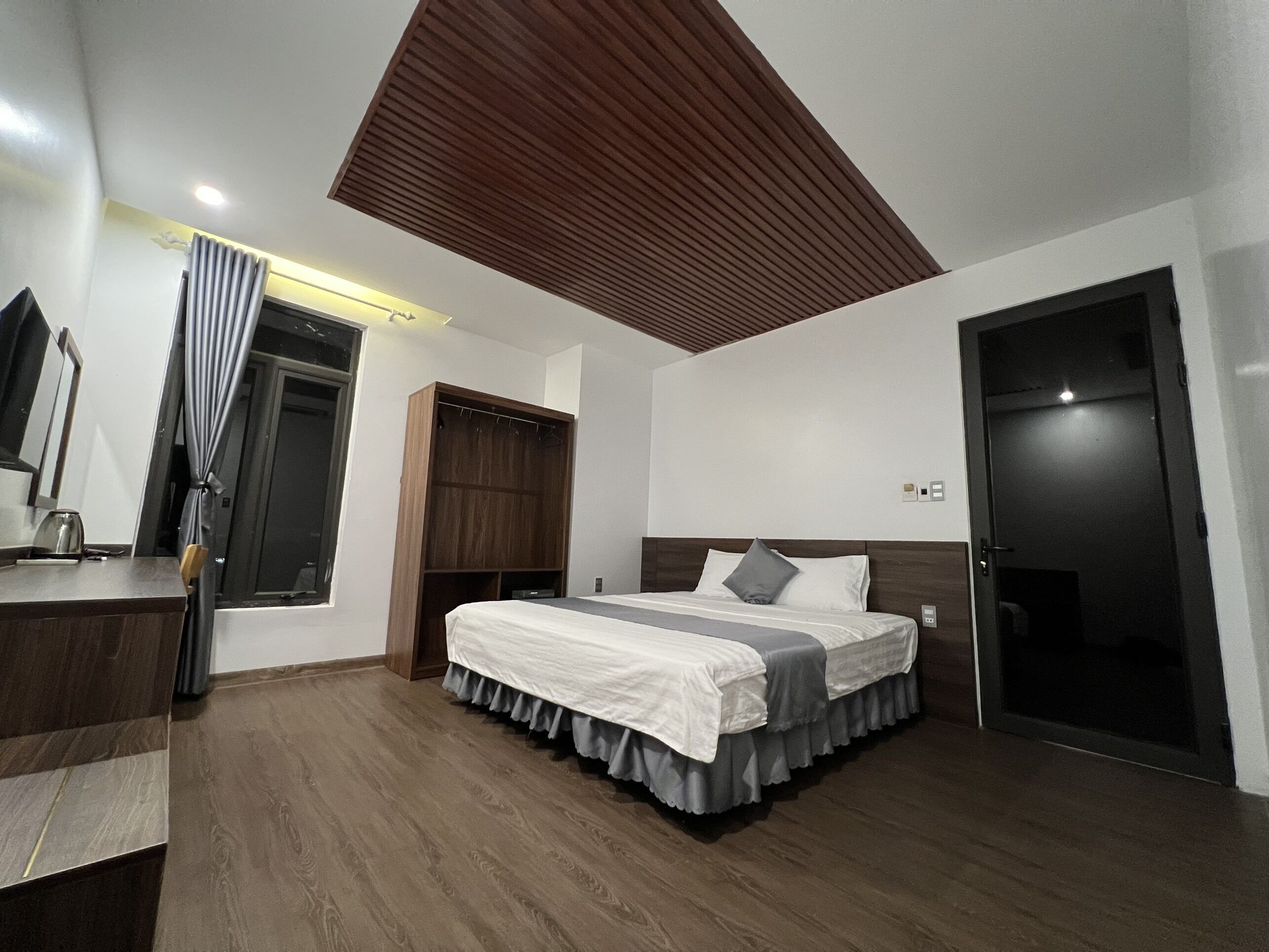 Un dormitorio moderno con una cama grande, un armario de madera y un techo con diseño de listones.