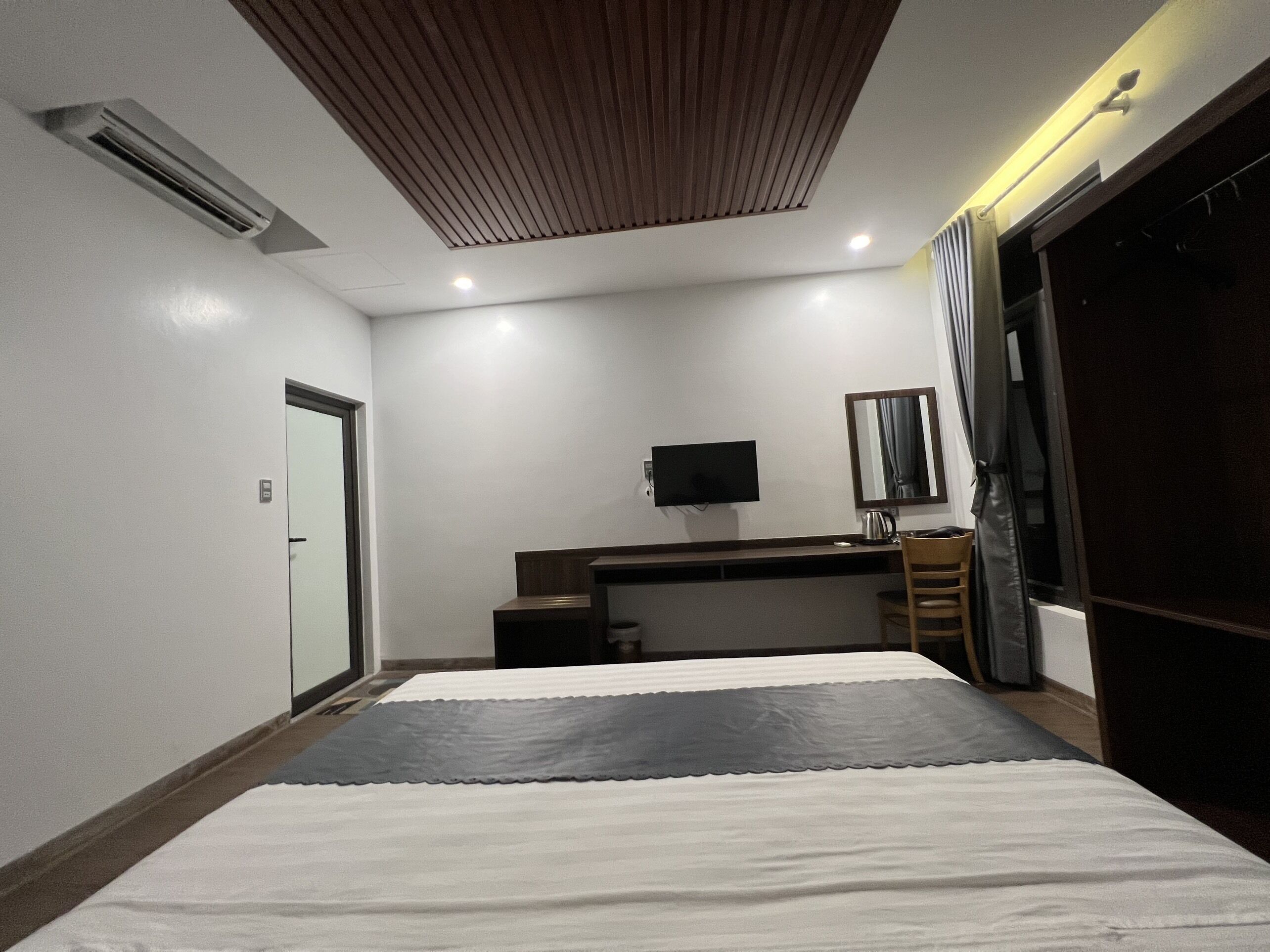 Une chambre à coucher comprenant un lit, un bureau, une télévision, un miroir et une armoire.