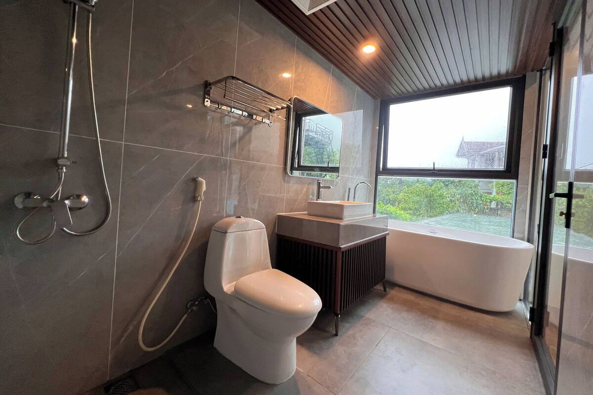 Uma casa de banho moderna com chuveiro, sanita, lavatório e banheira.