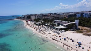 Un complejo turístico en la playa con varias edificaciones, una playa de arena y aguas turquesas cristalinas.