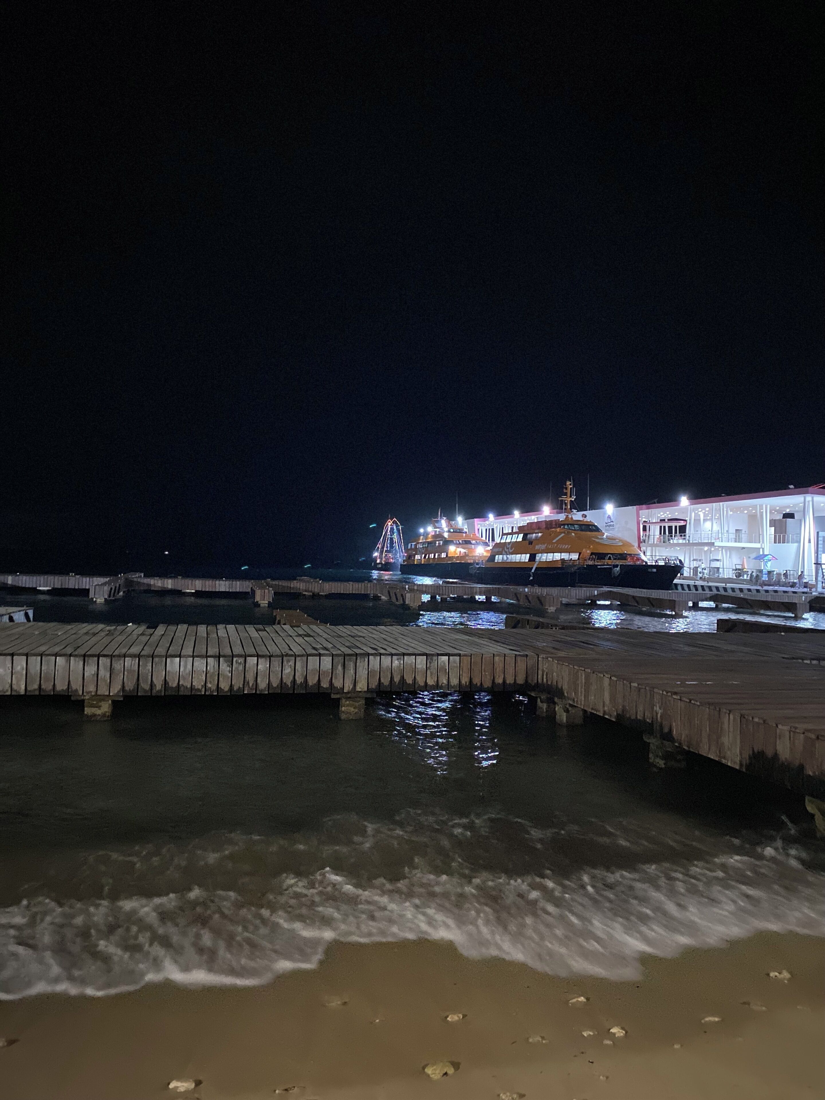A pier extending into the water with a building in the background.