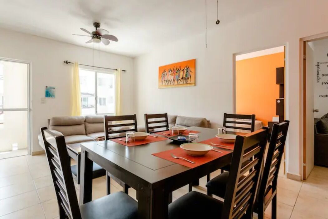 A dining area with a table set for four, a sofa, and a ceiling fan.